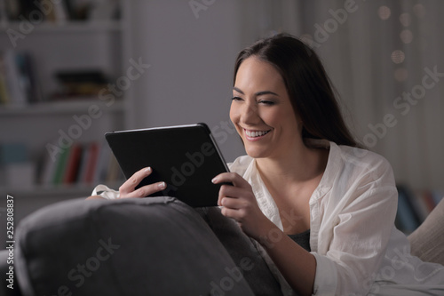 Happy woman watching media on tablet in the night