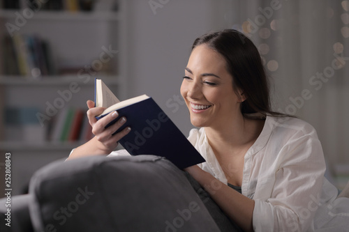 Happy tenant reading a book in the night at home