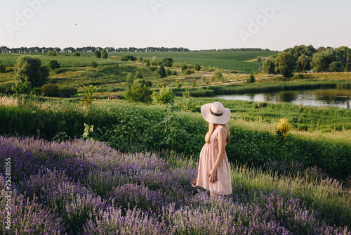 Pregnant girl blonde in a beige dress and straw hat. Lavender field. In anticipation of a child. The idea of a photo shoot. Walk at sunset. Future mom. Basket of flowers.