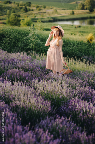 Pregnant girl blonde in a beige dress and straw hat. Lavender field. In anticipation of a child. The idea of a photo shoot. Walk at sunset. Future mom. Basket of flowers.