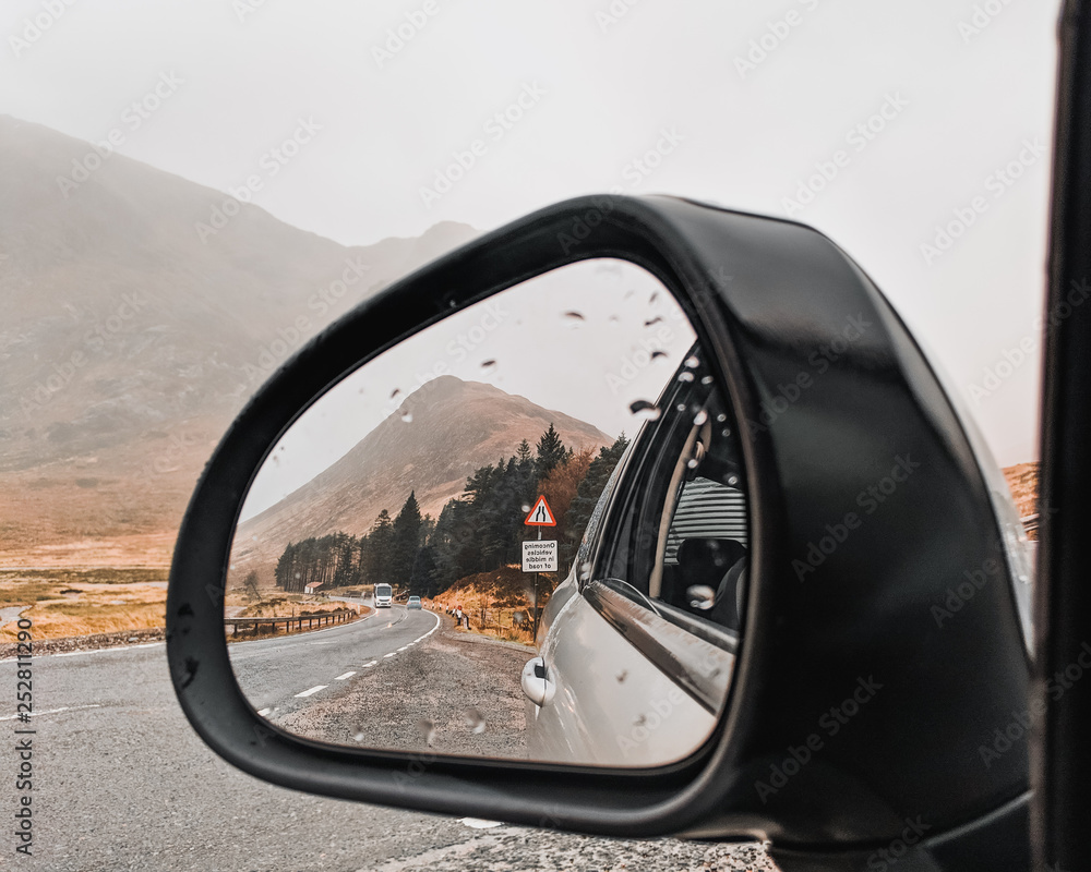 Fototapeta premium Reflection of a road and mountain in a car mirror