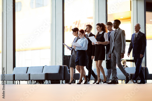 Large group of business people walking across office hall of lobby, copy space photo