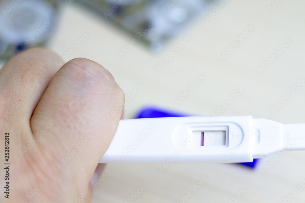 A man holds in his hand a pregnancy test with one strip. The concept of male impotence and infertility among men. Infertility in men.