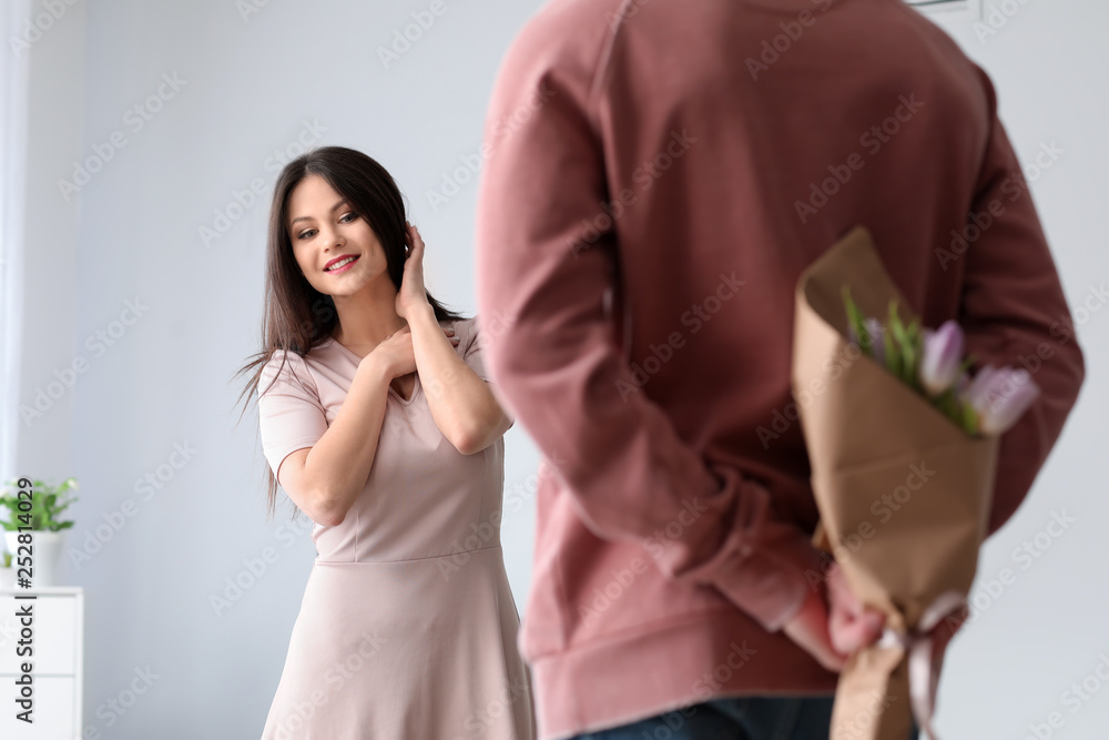 Young man hiding bouquet of flowers for his wife. 8 March celebration Young man hiding bouquet of flowers for his wife. 8 March celebration
