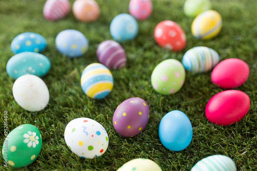 easter, holidays and tradition concept - colored eggs on artificial grass