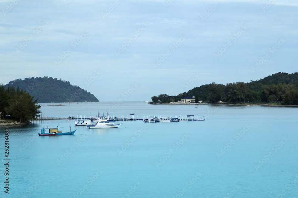 Boats and boats in the beautiful turquoise sea and the pier against the background of small islands, Malaysia, Island, the Strait of Malacca, concept of vacation, travel.