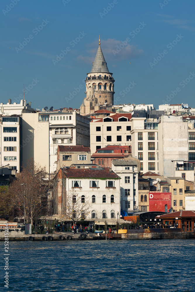 Fototapeta premium Galata Tower in Istanbul, Turkey. A view from water of Golden Horn bay. Sunny day. Outdoor shot