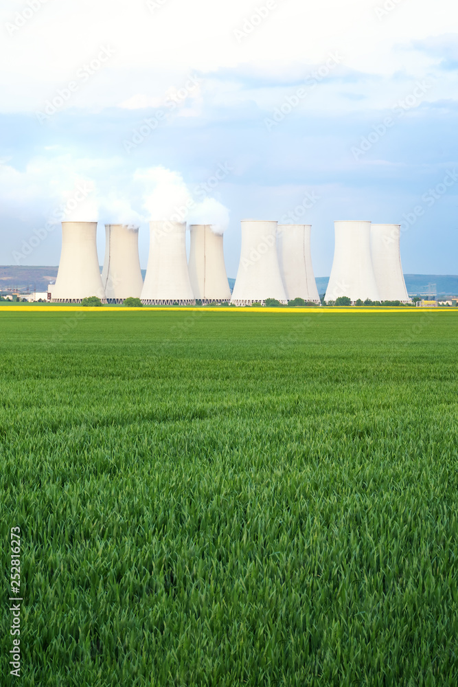 Green fields with cooling towers of nuclear power plant in background Green fields with cooling towers of nuclear power plant in background