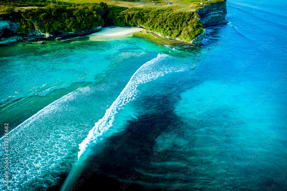 Aerial view of a tranquil tropical cove with big waves and turquoise water, Bali, Indonesia