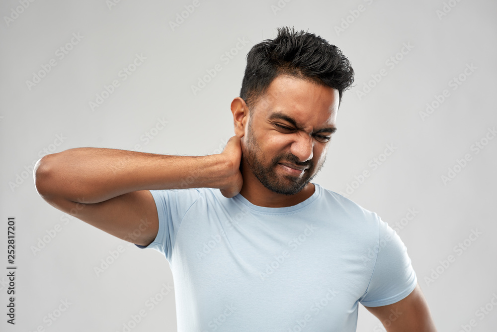health problem and people concept - unhealthy indian man suffering from neck pain over grey background health problem and people concept - unhealthy indian man suffering from neck pain over grey background
