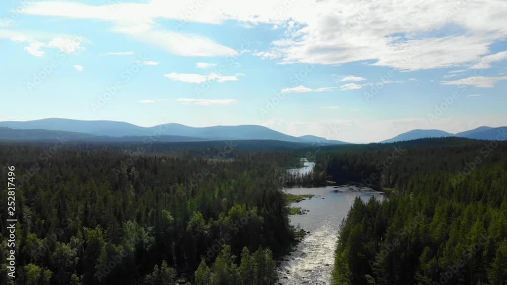 Top view of the beautiful river, which is located in the forest. In the background are mountains. Top view of the beautiful river, which is located in the forest. In the background are mountains.