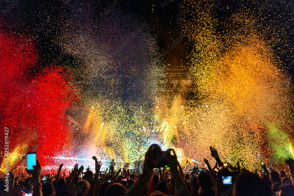 Multi colored confetti above the crowd on music festival.