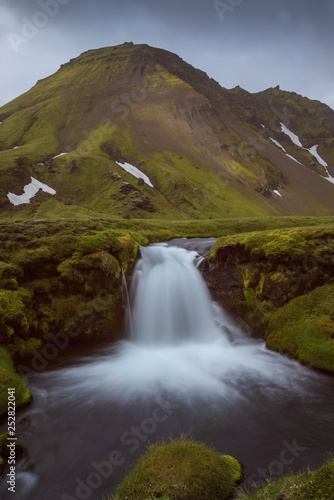 The Bl  fjallakv  sl Waterfall with golden clouds in the sky. The flowing water is captured by a long exposure. Amazing blue color of water from the glacier. Natural and colorful environment...