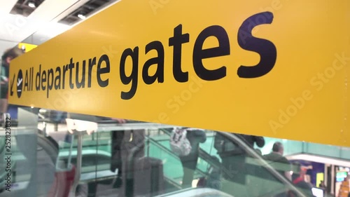 4K video clip of anonymous people traveling down an escalator at an airport terminal past a sign and towards departure gates