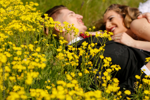 Happy beautiful wedding couple posing on hill with yellow flowers