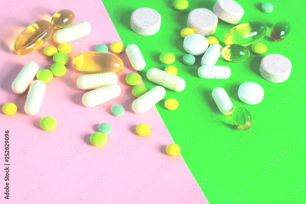 Tablets and capsules of different colors scattered.