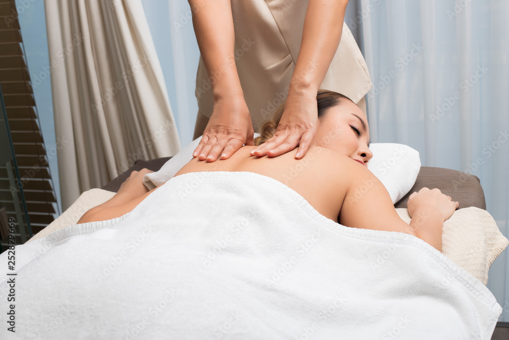 Obraz premium Body Massage on specific naked back of Mix Race Caucasian Asian woman by pressing fingers on pain or stress muscle point to release relax. Therapist Spa body massage woman hands treatment on customer