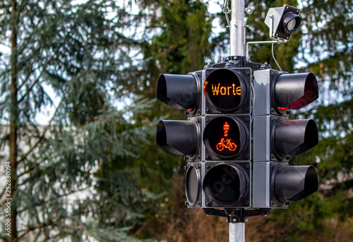 red traffic light with wait additional text warte sign