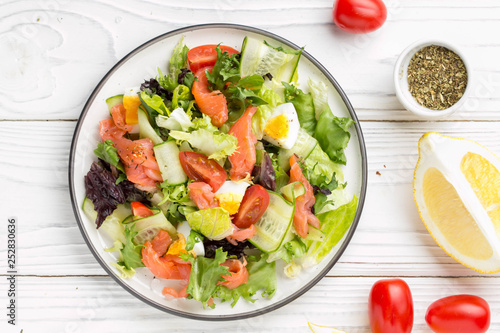 Salad with salmon, egg and vegetables (cherry tomatoes, cucumber, lettuce), delicious light lunch, healthy food