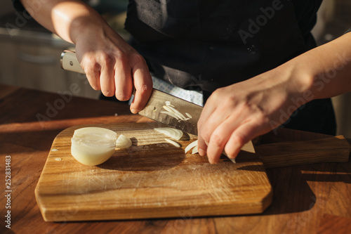Female chef chopping onions on a wooden board