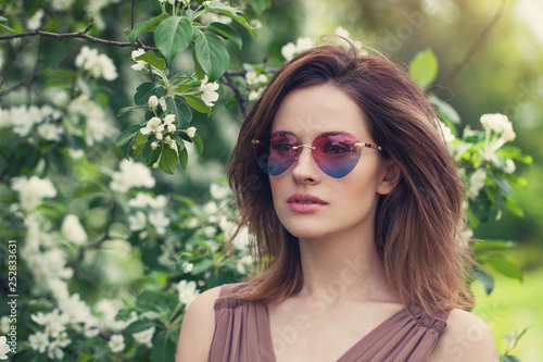 Young beautiful woman in sunglasses outdoors. Cute girl with brown layered hair,  spring portrait