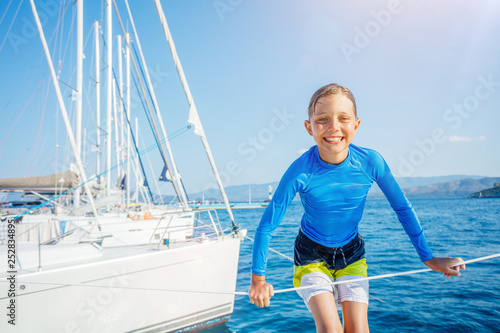 Little boy having fun on board of yacht on summer cruise. Travel adventure, yachting with child on family vacation.