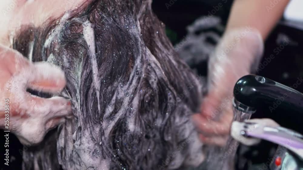 Hairdresser washes a girl hair with shampoo in a beauty salon close-up Hairdresser washes a girl hair with shampoo in a beauty salon close-up
