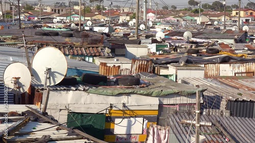 Establishing shot across rooftops of a typical township in South Africa, Gugulethu, with tin huts, poor people and poverty. photo