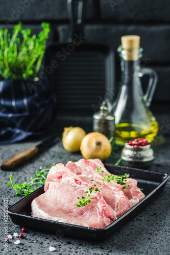 Raw meat, pork steaks on sheet pan with spices, olive oil, herbs, ready for cooking. Selective focus, space for text. photo