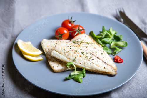 Fried fillet dorado (fish) with tomatoes, lemon and corn salad. Selective focus, close-up.