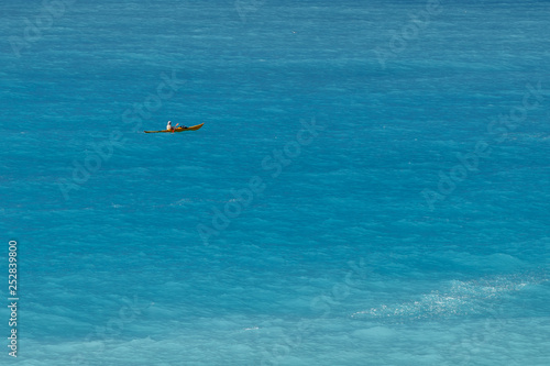 A man canoeing in  turquoise sea, view from faraway, holidays outdoor sport activity. Copy space.