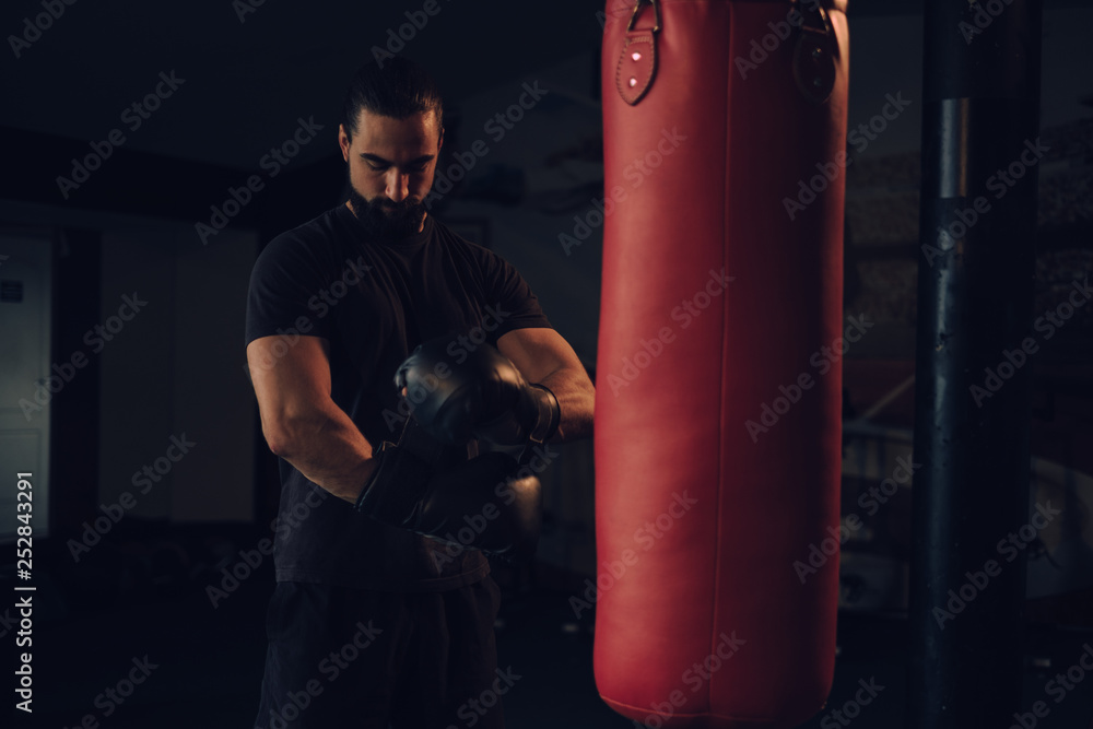 Boxer putting on gloves by the heavy bag