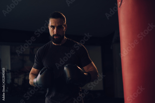 Canvas-taulu Boxer with gloves standing by the heavy bag