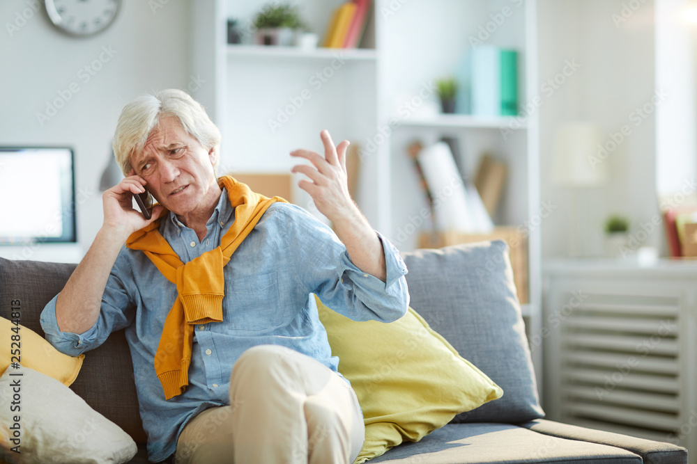 Obraz premium Portrait of frowning senior man speaking by phone arguing with somebody, copy space