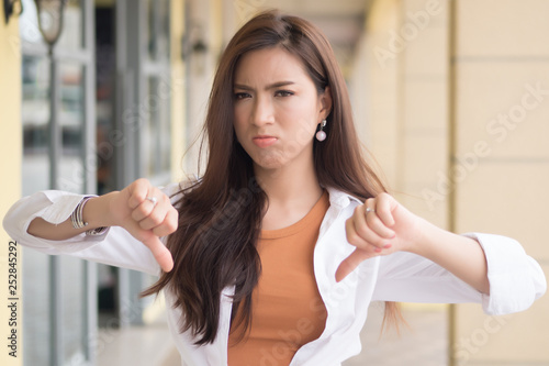 angry woman pointing thumb down  portrait of angry upset frustrated negative woman pointing up disapproval, no, bad, rejecting thumb down gesture  asian chinese woman young adult model © 9nong