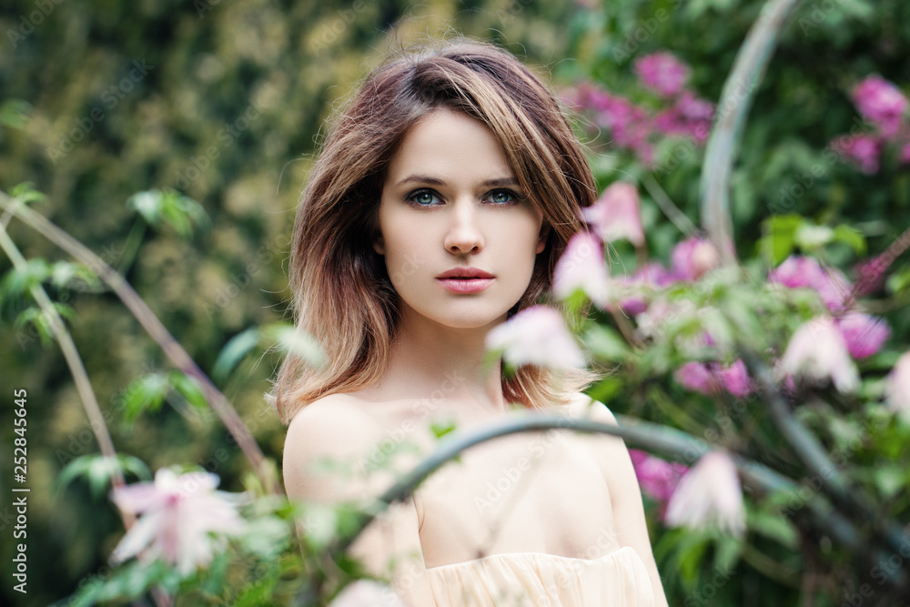 Beautiful woman face. Girl in flowers background outdoors Beautiful woman face. Girl in flowers background outdoors