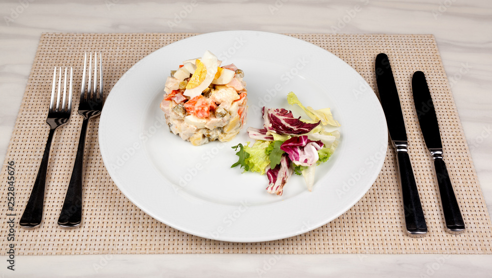 Salad Olivier with egg and cabbage on a white plate. Salad Olivier with egg and cabbage on a white plate.