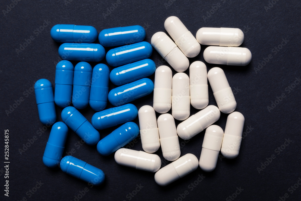 White and blue pills on black background White and blue pills on black background