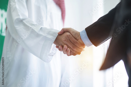 Fotografie, Tablou Arabian businessman hands shaking with Asian businessman in office, business con