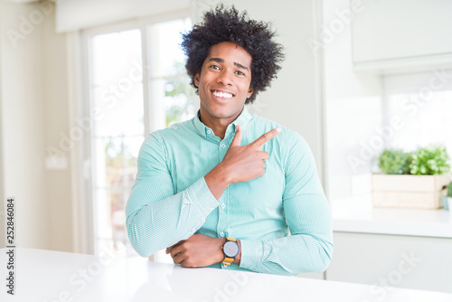 African American business man wearing elegant shirt cheerful with a smile of face pointing with hand and finger up to the side with happy and natural expression on face