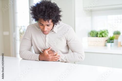 African American man at home with hand on stomach because nausea, painful disease feeling unwell. Ache concept. © Krakenimages.com