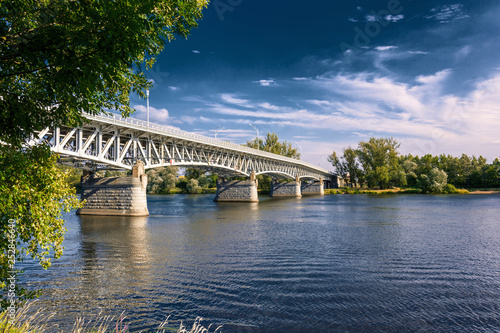 Steel bridge across the river Elbe in the town of Litomerice in the Czech Republic. Bridge in summer sunny day. Metal construction of arched bridge with pillars over the river. Architectural monument 