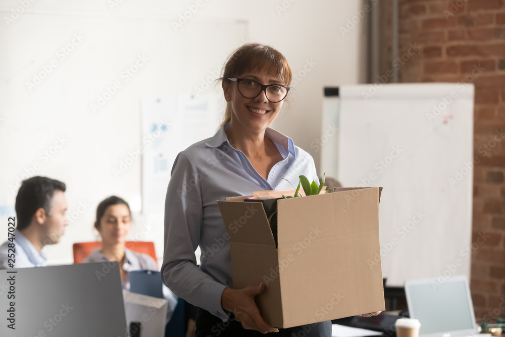 Smiling middle aged businesswoman holding box looking at camera Smiling middle aged businesswoman holding box looking at camera