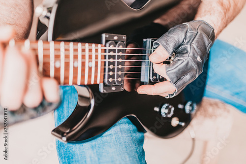 A man in black leather gloves plays hard rock on a left-handed electric guitar photo