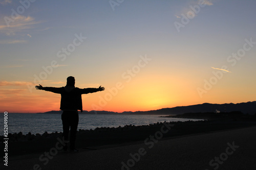 夕方の海辺に立つ男のシルエット © ヒヤスン子