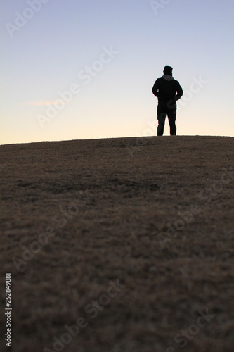 夕方の丘に立つ男のシルエット