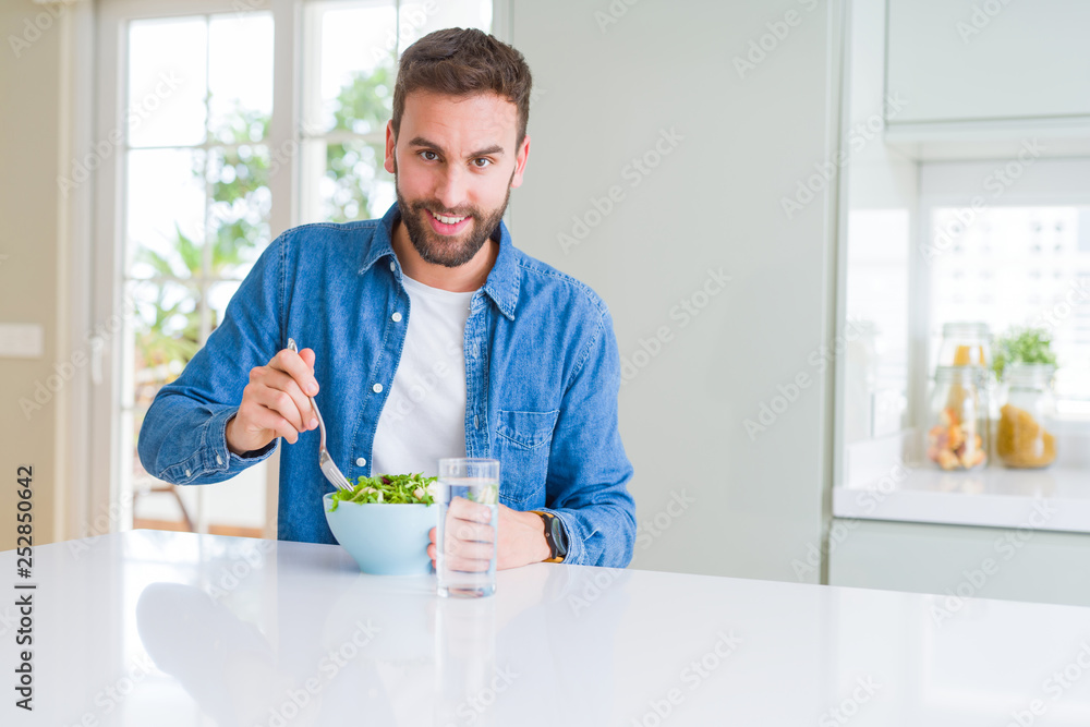 Handsome man eating green peas at home