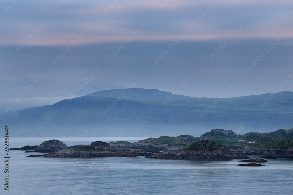 View of Isle of Mull cliffs and Ben More mountain over Sound of Iona from Isle of Iona Abbey at dusk Scotland UK