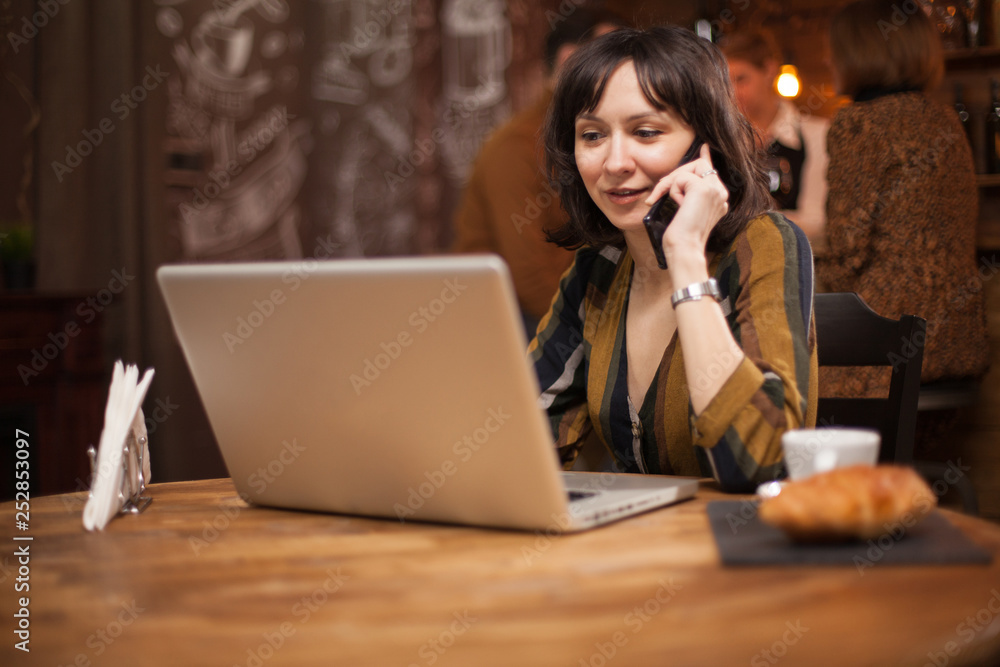 Young businesswoman talking on the while browsing on her laptop Young businesswoman talking on the while browsing on her laptop
