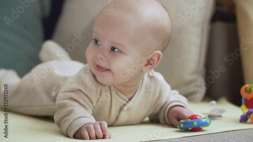 Cute baby luying on bed and smiling at camera. Childhood and babyhood concept photo